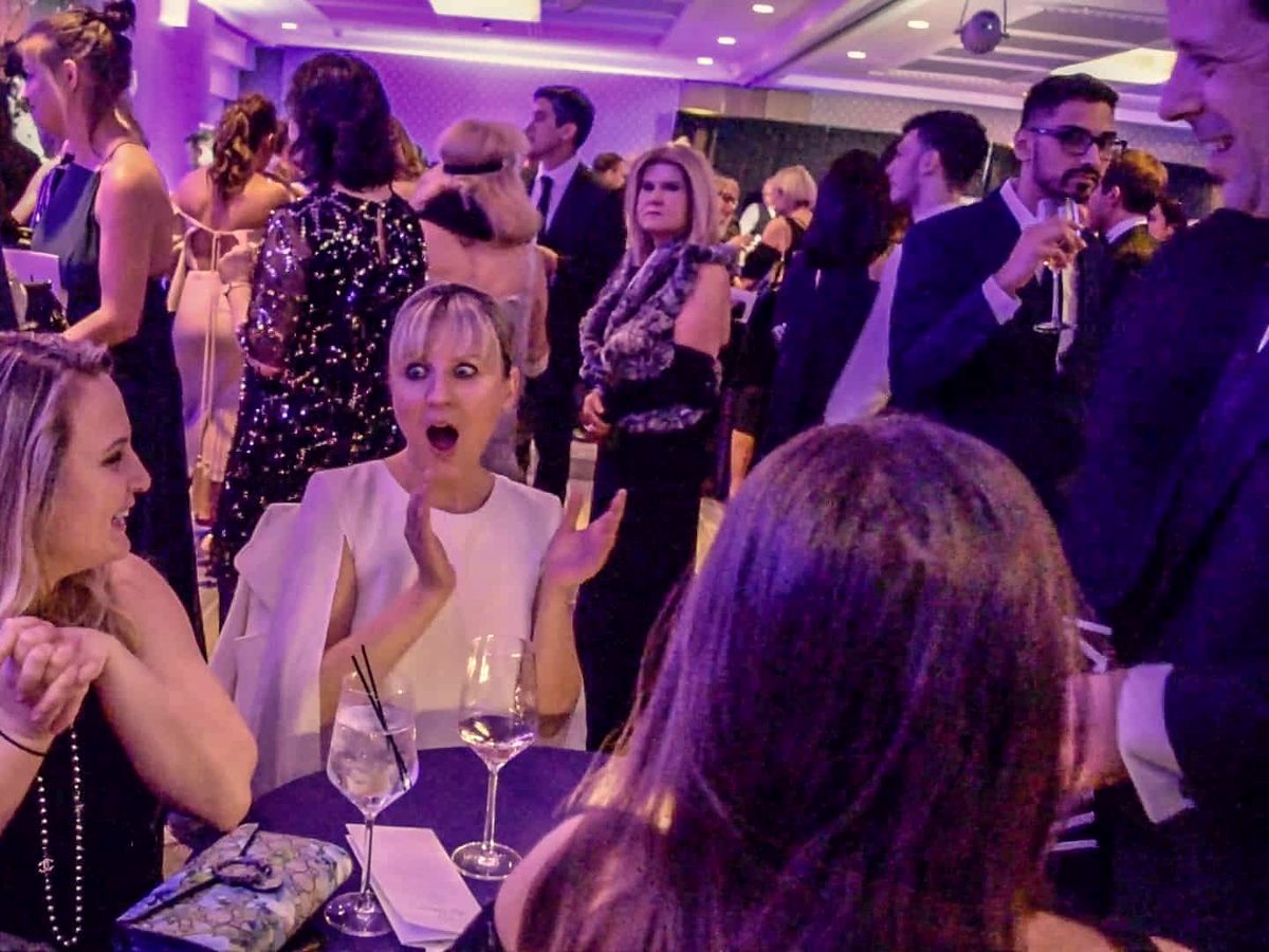 Guests reacting with delight during close-up magic at a corporate holiday gala