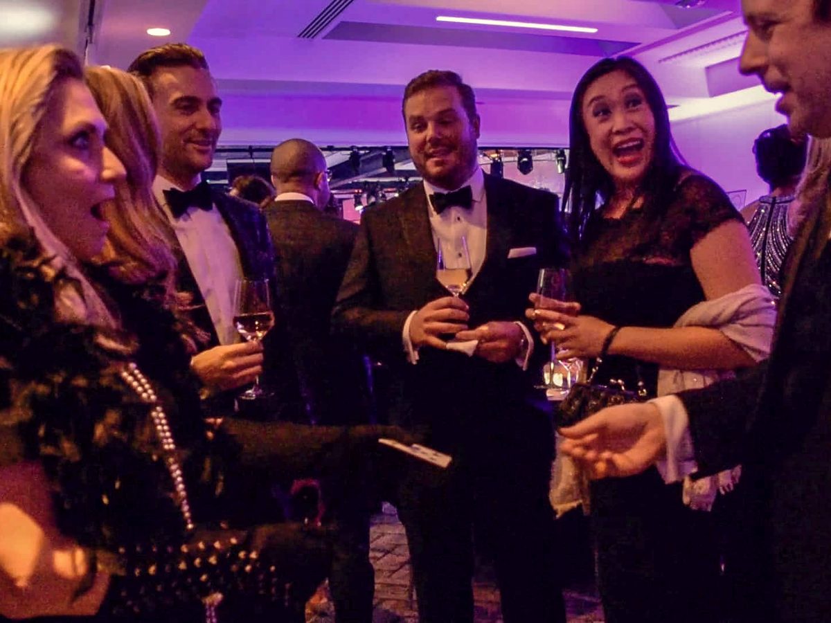 Guests reacting to a card reveal during cocktail hour at a corporate gala