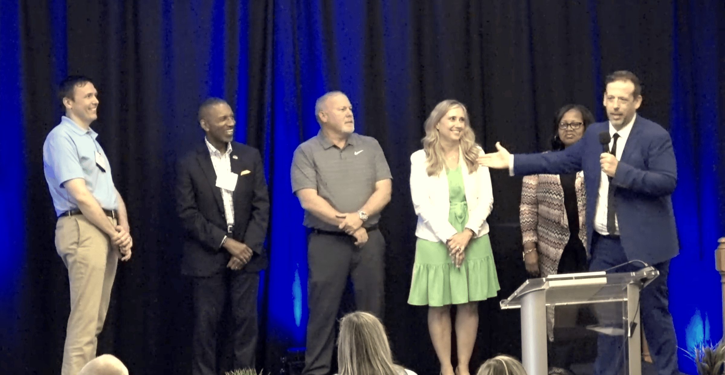Eric Lerner performing a corporate magic show on stage with volunteers from the audience