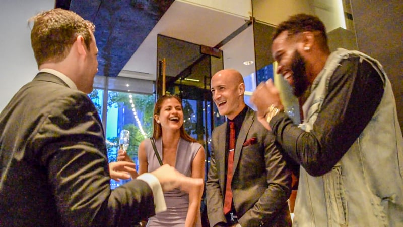 Guests laughing together during close-up magic at a cocktail hour