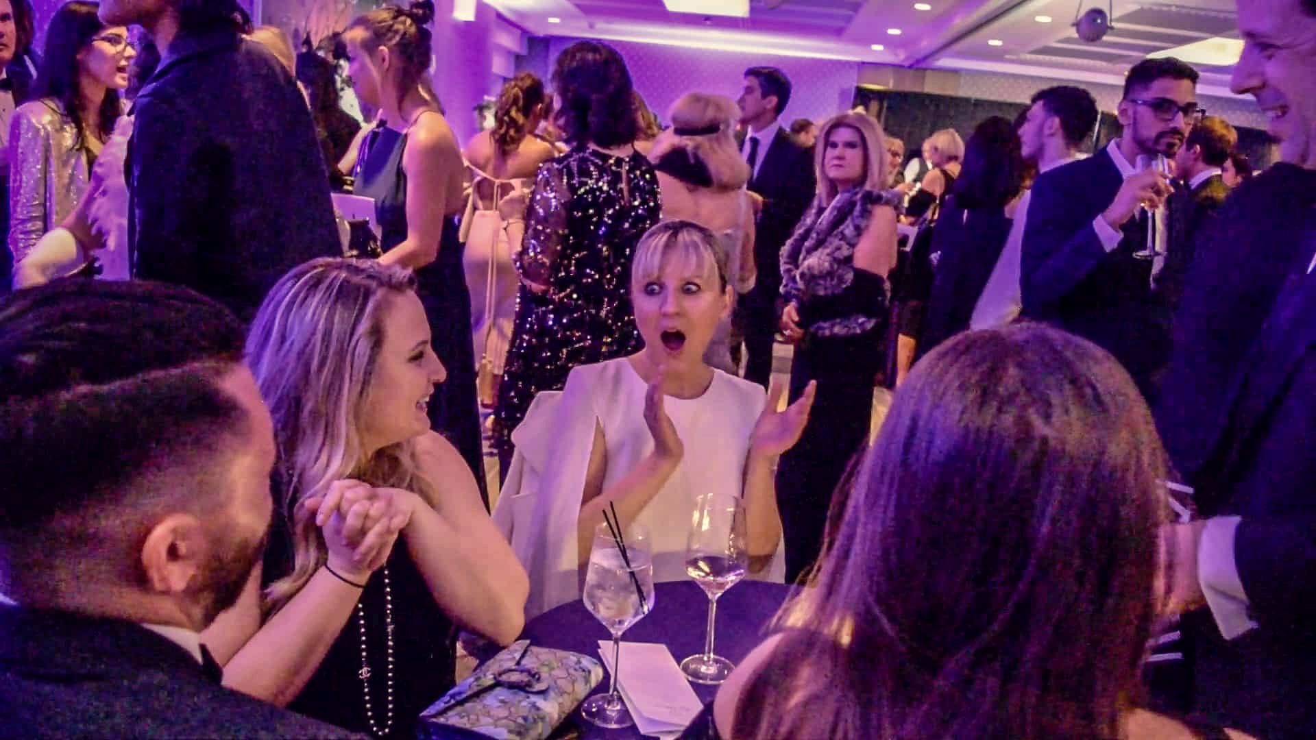 Guests laughing together with drinks in hand as Eric performs close-up magic
