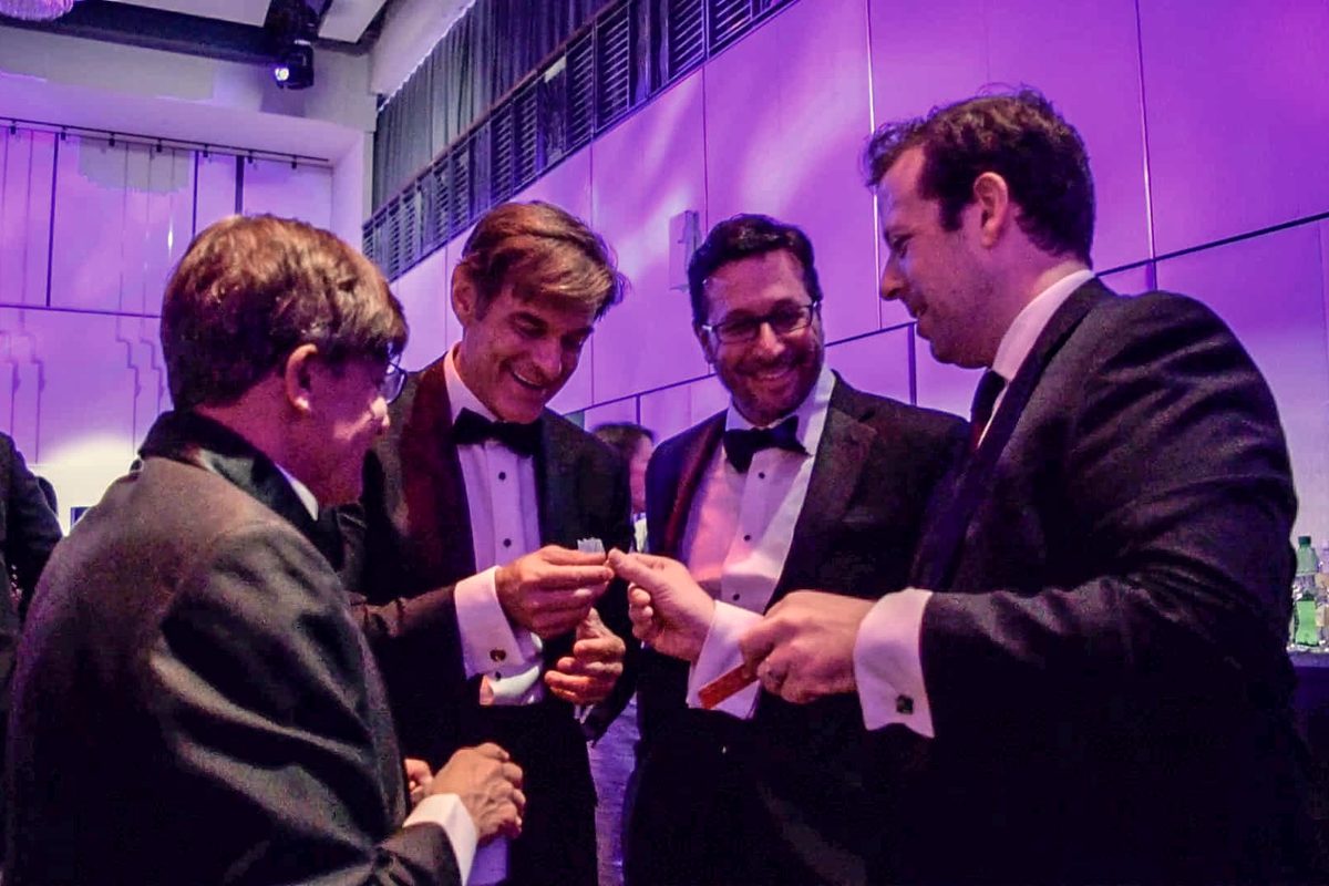 Guests in black tie watching close-up magic during a wedding cocktail hour